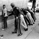 A Michigan State police officer searches a youth on Detroit’s 12th Street where looting was still in progress after the previous day’s uprising. July 24, 1967